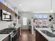 Open-concept kitchen featuring stainless steel appliances, a stylish gas range, and a view into the living room at 1996 W 66Th Ave, Denver, CO 80221