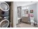 Cozy bathroom featuring a stacked washer and dryer, tile shower and tub, wood vanity, and unique wood-look flooring at 3100 Huron St # 4Q, Denver, CO 80202