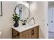 Bright bathroom showcasing a wood vanity, round mirror, and modern fixtures at 9263 E Nassau Ave, Denver, CO 80237