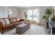 Bright living room featuring a comfortable brown leather sofa, plants, and large windows at 4653 S Yank St, Morrison, CO 80465