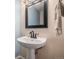 Elegant bathroom with a pedestal sink and black framed mirror, creating a minimalist aesthetic at 14753 E Alabama Pl, Aurora, CO 80012