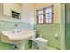 Retro bathroom with pedestal sink, tile, toilet, and refinished hardwood floors at 2285 N Monaco Pkwy, Denver, CO 80207