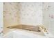 Close-up of bathtub with gold fixtures and floral wallpaper in the bathroom at 2285 N Monaco Pkwy, Denver, CO 80207