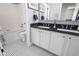 White bathroom with basket-weave floors, tub/shower combo, and double vanity with black countertop at 6088 Rogers Cir, Arvada, CO 80403