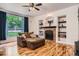 Comfortable living room featuring hardwood floors, built-in bookshelves, and a brick fireplace at 7420 S Houstoun Waring Cir, Littleton, CO 80120