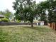Large grassy backyard with mature tree, wooden fence, and storage shed provides a private outdoor space at 4115 S Vincennes Ct, Denver, CO 80237