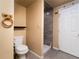 Compact bathroom with neutral tones, tiled shower, and storage shelf at 940 S Geneva St, Aurora, CO 80247