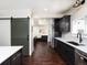 Open kitchen showcases dark cabinets, stainless steel appliances, white counters, and a barn door, offering modern convenience at 940 S Geneva St, Aurora, CO 80247