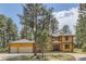 Two-story log home with a two-car garage and a curved driveway at 7350 Fremont Pl, Larkspur, CO 80118