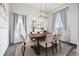 Elegant dining room with a wooden table, neutral chairs, modern chandelier, and large windows at 22580 E Eads Cir, Aurora, CO 80016