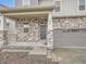 Home exterior with attractive stone details, a two-car garage, and manicured landscaping at 553 Homestead Ave, Brighton, CO 80601