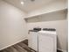 Convenient laundry room with washer, dryer, open shelving, and wood-look flooring at 553 Homestead Ave, Brighton, CO 80601