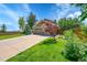 Beautiful home featuring a lush green lawn, mature trees, and a long driveway leading to a spacious three-car garage at 16500 Hitching Post Cir, Parker, CO 80134