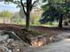 Picturesque backyard featuring mature trees, lush grass, and a charming stone retaining wall at 2261 W Briarwood Ave, Littleton, CO 80120