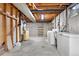 Unfinished basement with concrete flooring, utility connections, laundry area, and partial framing at 2842 S Newport St, Denver, CO 80224