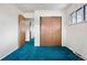 Bedroom featuring closet with sliding doors, bright teal carpeting, and ensuite access at 2842 S Newport St, Denver, CO 80224