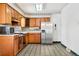 Well-lit kitchen featuring oak cabinets, stainless steel refrigerator, and tiled floor at 2842 S Newport St, Denver, CO 80224