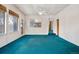 Bright living room featuring large windows, a ceiling fan, and teal carpeting at 2842 S Newport St, Denver, CO 80224