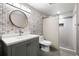 Updated bathroom with modern vanity, round mirror, and tiled shower at 2451 S Fenton Dr, Lakewood, CO 80227