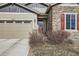 Inviting front entrance with stone facade, red door, and landscaping at 19713 E 63Rd Pl, Aurora, CO 80019