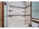 Close-up of bathtub, shower, and shelving in a bathroom with decorative tile at 10441 Routt Ln, Broomfield, CO 80021