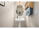 Small powder room with pedestal sink, oval mirror, and wooden shelf at 8445 Braun Loop, Arvada, CO 80005