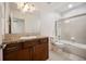 Bright bathroom features a vanity with a dark wood cabinet, a large mirror, and a shower-tub combo with sliding glass doors at 4400 S Ensenada St, Aurora, CO 80015