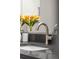 Close-up of a modern bathroom faucet and dark countertop, with a vase of yellow flowers at 2528 Concord Cir, Lafayette, CO 80026