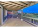 Covered outdoor patio with wood railing, offering serene views of the landscaped backyard at 1838 Mountain Daisy Ct, Highlands Ranch, CO 80129