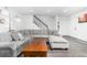 Bright living room featuring a large sectional sofa, wood floors and modern staircase at 4663 S Lowell Blvd, Denver, CO 80236