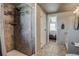 Well-lit bathroom with a tiled shower, a view of the main bedroom, and a double sink vanity at 16491 County Road 32, Platteville, CO 80651