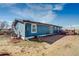 Exterior showcasing the home's blue siding, ample yard space, and patio area with outdoor seating at 16491 County Road 32, Platteville, CO 80651