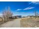 View of the property and blue home with a gravel drive at 16491 County Road 32, Platteville, CO 80651