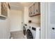 Bright laundry room with gray cabinets, wood-look floors, and a new, front-load washer and dryer at 16491 County Road 32, Platteville, CO 80651