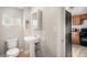 Bathroom featuring pedestal sink, toilet, medicine cabinet, small window, and access to kitchen at 4764 High St, Denver, CO 80216