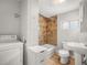 Full bathroom offers washer, dryer, tile shower-tub, white vanity, toilet, and light wood-look floors at 4764 High St, Denver, CO 80216
