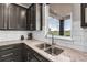 Stylish kitchen featuring granite countertops, subway tile backsplash, and stainless steel sink with neighborhood view at 1174 Williams Loop, Elizabeth, CO 80107