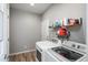 Well-lit laundry room with a washer, dryer, wooden shelving, and light wood-look flooring at 7958 Tejon St, Denver, CO 80221