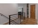 Hallway showcasing modern railing, hardwood floors, and a glimpse into the updated kitchen at 2184 S Braun Way, Lakewood, CO 80228