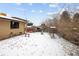 Snowy backyard featuring trees, shrubs and a wooden bench at 3860 Dudley St, Wheat Ridge, CO 80033