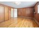 Bedroom with wood paneling, light hardwood floors, and a closet for storage at 3860 Dudley St, Wheat Ridge, CO 80033