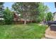 Lush backyard showcasing a well-manicured lawn, mature trees, and a patio with outdoor seating, perfect for relaxation at 9631 S Dover Way, Littleton, CO 80127