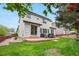 Two-story home with a backyard featuring a concrete patio with outdoor furniture and a well-maintained lawn at 9631 S Dover Way, Littleton, CO 80127