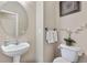 Cozy powder room featuring pedestal sink, round mirror, fresh white towels, and neutral colors at 9631 S Dover Way, Littleton, CO 80127