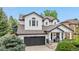 Charming two-story home with a dark gray two-car garage, black trim, covered porch, and manicured landscaping at 9631 S Dover Way, Littleton, CO 80127