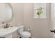 Half bathroom featuring a pedestal sink, decorative mirror, and a sunlit window at 3325 Umber Cir, Castle Rock, CO 80109
