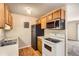 Functional kitchen with white appliances, wood cabinets, and modern updates at 10211 Ura Ln # 304, Thornton, CO 80260