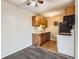 Compact kitchen with white appliances and oak cabinets adjacent to the carpeted living area at 10211 Ura Ln # 304, Thornton, CO 80260