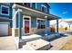 Inviting front porch with brick accents, sturdy columns, and a brightly colored front door at 2091 Basil St, Strasburg, CO 80136