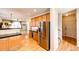 An open kitchen leading into living areas featuring stainless fridge and wood floors at 2091 Basil St, Strasburg, CO 80136